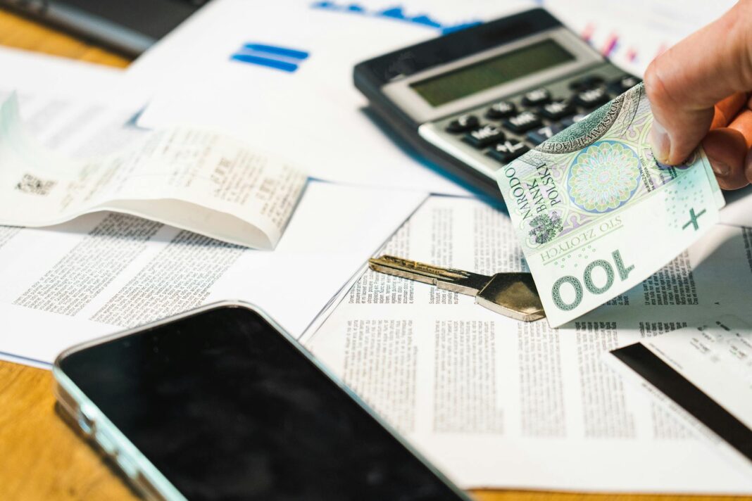 Rachunki telefoniczne, kalkulator i banknoty złotowe na biurku
