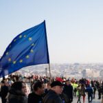 Przeprowadzka do innego kraju UE a gwarancja i serwis sprzętu elektronicznego Tłum ludzi idących ulicą z powiewającą flagą Unii Europejskiej