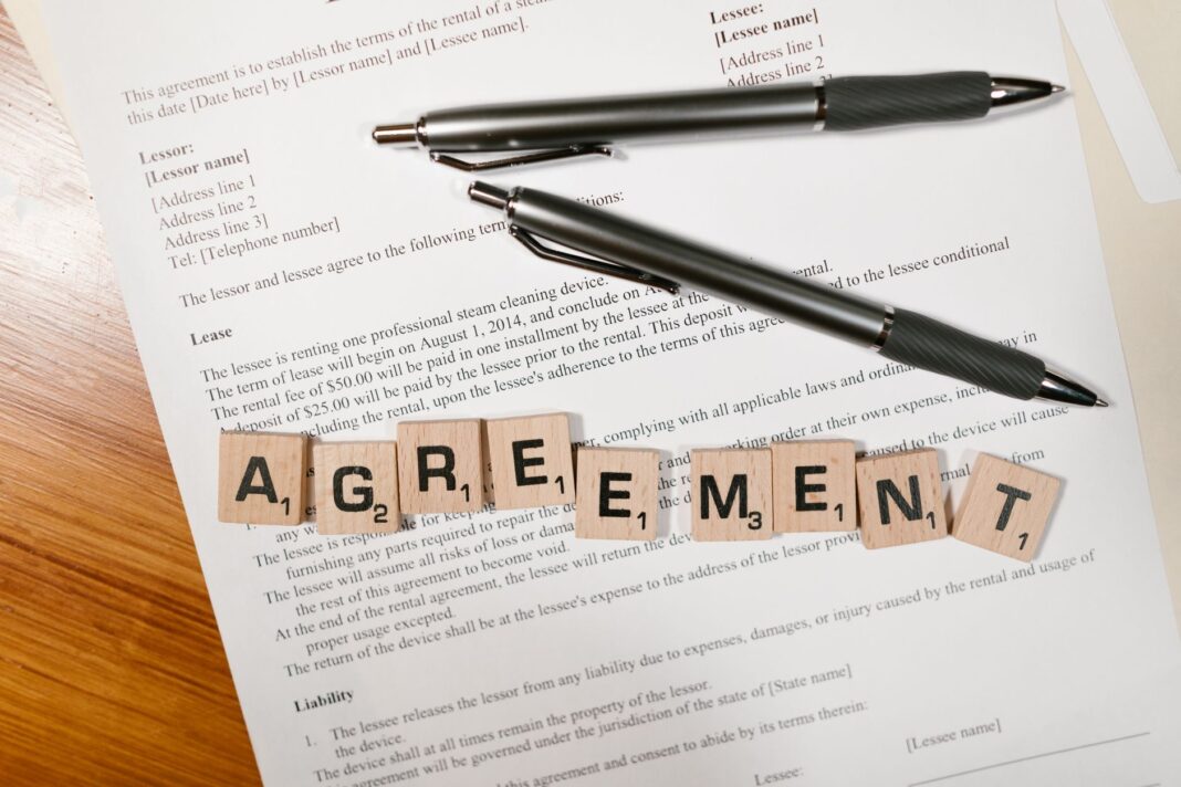 Dokument z napisem AGREEMENT ułożonym z kostek i dwiema długopisami Dokument z napisem AGREEMENT ułożonym z kostek i dwiema długopisami