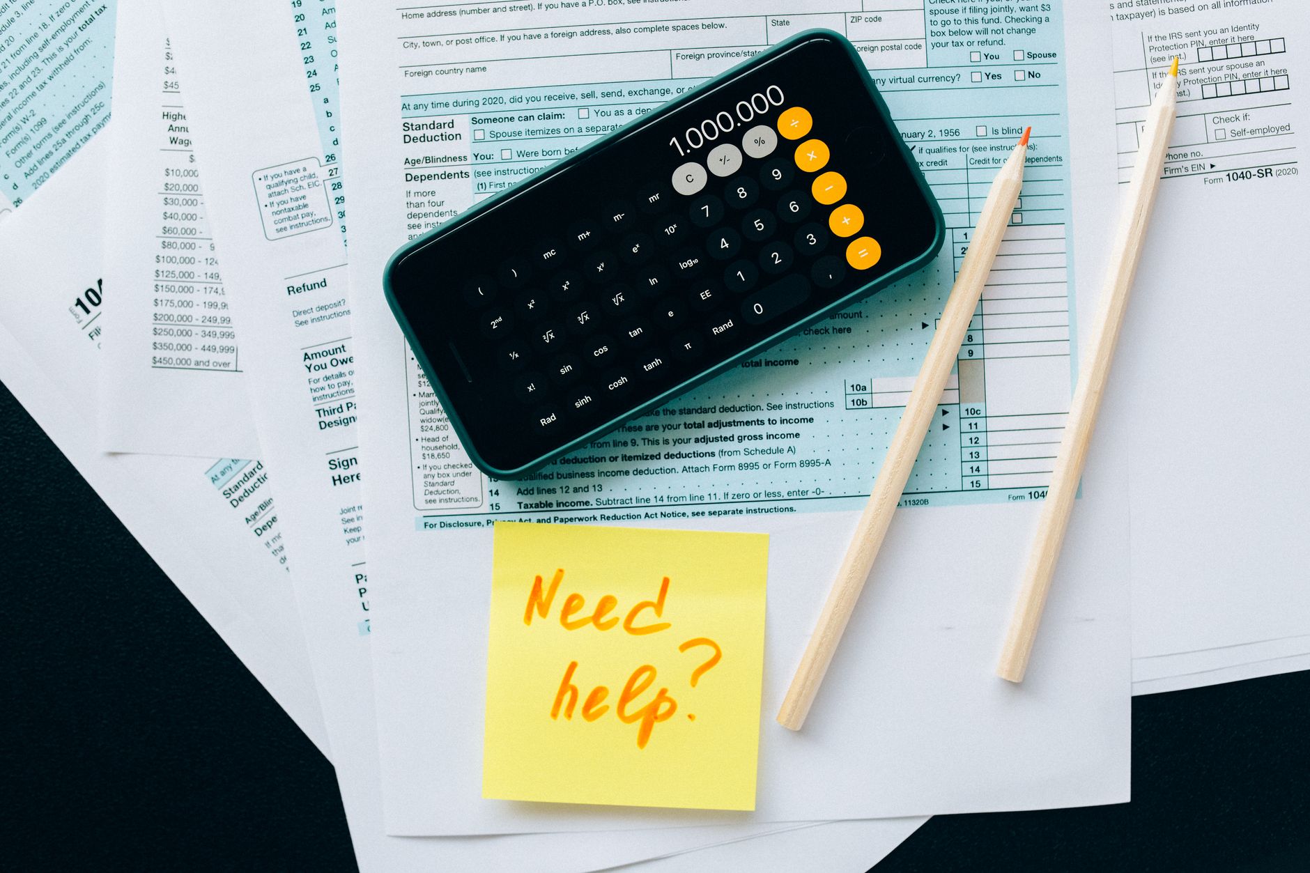 Dokumenty podatkowe z kalkulatorem i notatką z napisem Need help?