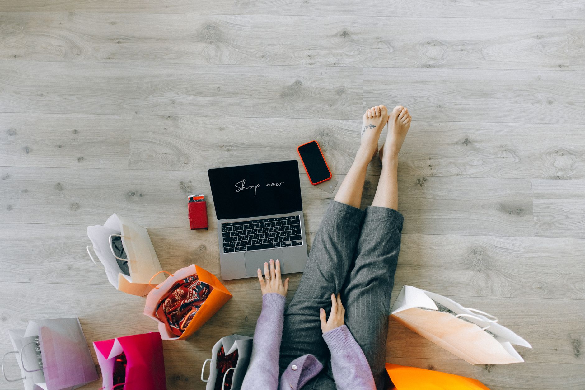 Kobieta robi zakupy online przy laptopie z papierowymi torbami