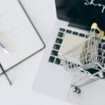 Miniaturowy koszyk zakupowy na klawiaturze laptopa przy zakupach online